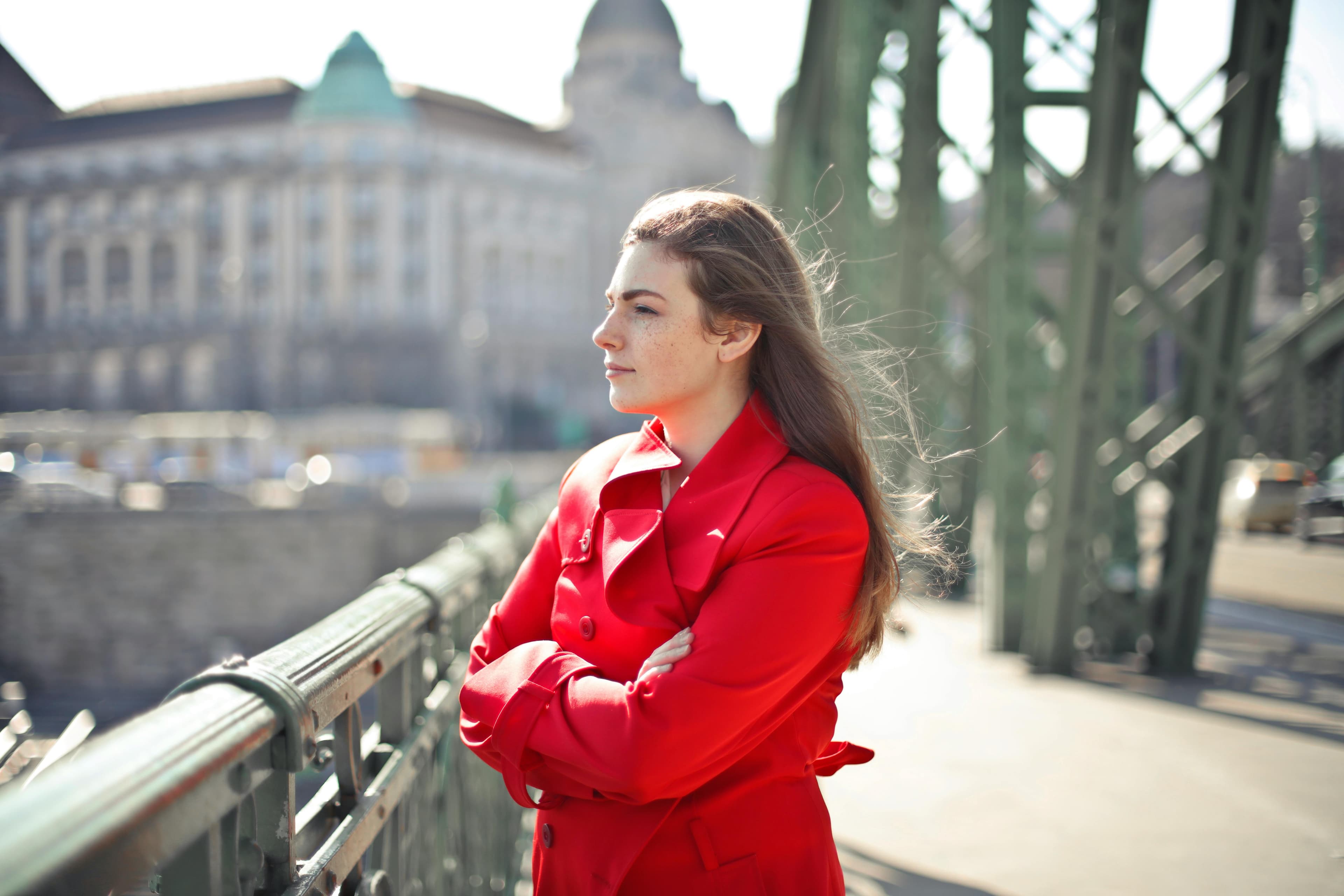 Young woman cityscape red jacket looking off bridge Young woman cityscape red jacket looking off bridge